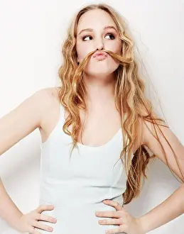 Posed Prints: Fun-loving and playful. Playful young woman making a moustache with her hair against a white background