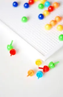 Pick Prints: fun with a pin button game for kids white plate with colorful pins
