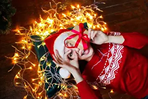 Bedtime Prints: Funny cute woman lying on floor and holding present in room with christmas decorations at home