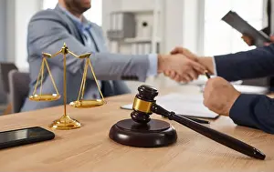 Advisor Prints: Gavel and justice scales on table, with lawyer and client shaking hands in background