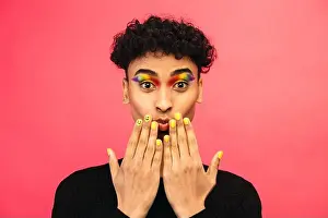Generation Z Prints: Gay man wearing rainbow colored eye shadow and smiley face on fingernail on red background
