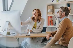 Beautiful Woman Prints: General practitioner using computer while sitting by patient at doctor's office