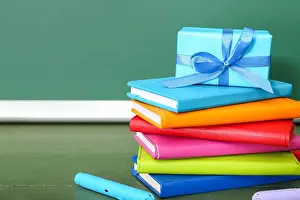 Blackboard Prints: Gift box with books and colorful markers on table in classroom
