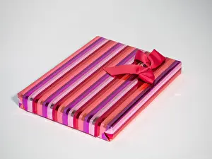 Christmas Gift Prints: gift wrapped in striped shiny wrapping paper with red bow sat on white background