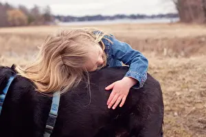 Girl (4-5) hugging her dog on field
