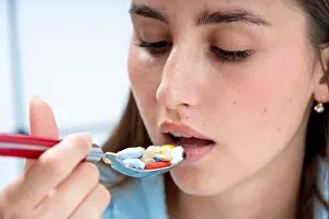 Pills Prints: a girl brings a spoon filled with pills to her mouth