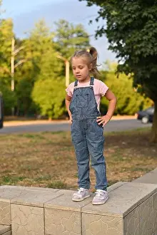 Hips Prints: girl in denim jumpsuit and pink T-shirt stands on concrete wall