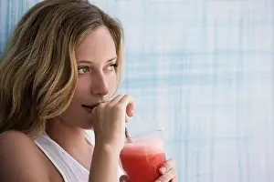 Youngster Prints: Girl drinking red smoothie, up against blue wall