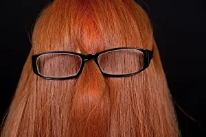 Redhead Prints: Girl with long red hair covering her face and wearing glasses against a black background