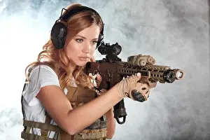 Girl marksman in sniper gear holding sniper rifle in hand aiming at enemys head in dark smoky background