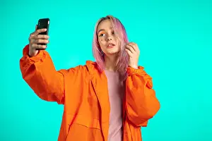 Shocked Prints: Girl with pink hair and extraordinary appearance make selfie on blue background