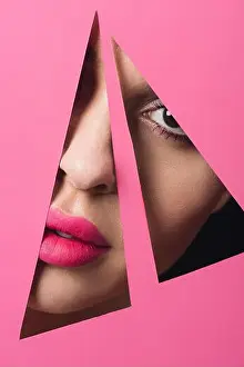 Triangles Prints: Girl with pink lips looking at camera across triangular holes in paper on black background