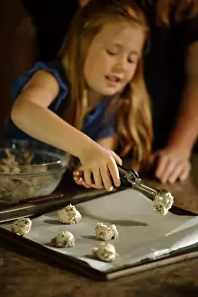 Mid Adult Woman Prints: Girl putting cookie dough on baking sheet using serving scoop at home