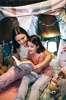Pajama Prints: Girl reading with her mother in a makeshift tent at home