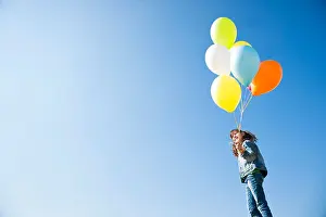 Sideview Prints: Girl standing with balloons under blue sky