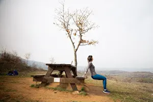 Exhausted Prints: Girl trains in nature while leaning on the bench