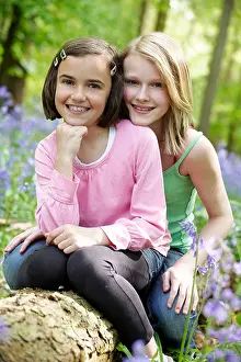 Cheek Prints: Two girls sitting together in a wood full of bluebells