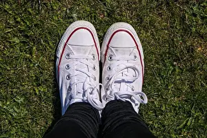 Girl's white Converse trainers standing on short grass looking from above