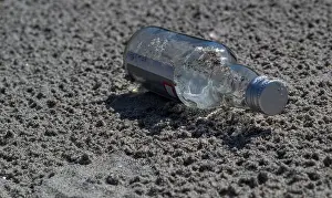 Salt Water Prints: A glass bottle on the sand. Discarded glass bottle lying on sandy beach