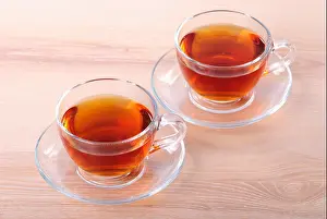Igniting Prints: Two glass cup of black tea on wooden table