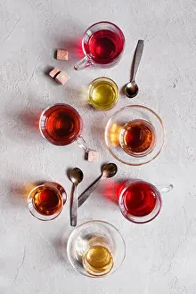 Hibiscus Prints: Glass cups with various types of tea on the textured grey table, top view