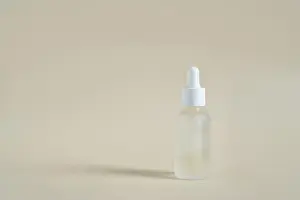 Skincare Prints: Glass Dropper Bottle Standing Upright On Smooth Beige Tabletop In Minimalist Studio Setting With Soft Shadow And