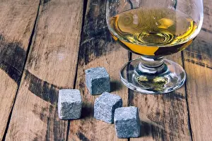 Liquor Prints: Glass of whiskey with stones. Golden whiskey in glass with cooling stones on a wooden table