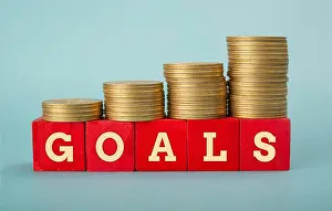 White Collar Worker Prints: Goals word wrritten on wooden blocks with Coin Stack going up