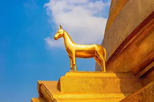Asian Culture Prints: Golden Horse statue on the roof of a Buddhist temple against a blue sky