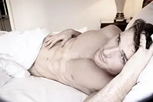 Waking Up Prints: Good looking naked man with six pack abs and blue eyes eyes lying naked in bed