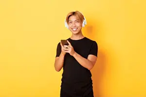 Podcast Prints: Good-looking smiling, pleased asian guy in wireless headphones