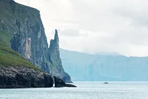 Gorgeous faroese landscape with famous Witches Finger cliffs and dramatic cloudy sky from Trollkonufingur viewpoint. Vagar island, Faroe Islands, Denm