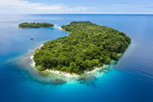 A gorgeous, tropical island is surrounded by reef in Papua New Guinea. This remote area is part of the Coral Triangle due to its marine biodiversity