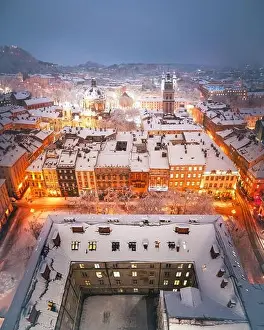 Snowstorm Prints: Gorgeus cityscape of winter Lviv city glowing by city lights with roofs covered by snow from top of town hall
