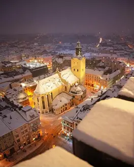 Gorgeus cityscape of winter Lviv city with roofs covered by snow from top of town hall, Ukraine, Europe. Latin Cathedral glowing by city lights