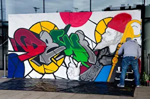 Sant Prints: Graffiti artist spraying St Davids Day art work, Millennium Centre, Cardiff, Wales