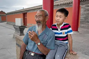 Adult Man Prints: Grandfather smoking cigarette and grandson enjoy each other's company as sun sets over city park on Obo Hill