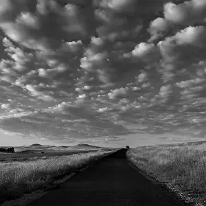 Grayscale Prints: A grayscale of a sunrise over a road with cloudy sky in the background in Cooma