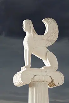 Greek Sphinx statue standing on top of a ionic order pillar on a cloudy day in Greece