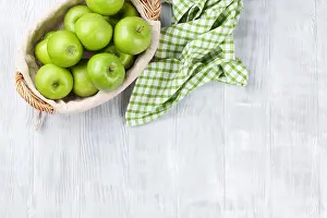 Apples Prints: Green apples in basket over wooden table. Top view with copy space