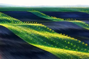 Green, brown and yellow waves of the agricultural fields of South Moravia, Czech Republic. Rural spring landscape with colored striped hills with