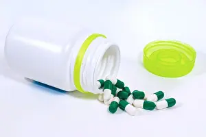 Remedy Prints: Green medicine tablets inside and outside an white plastic bottle on an white background