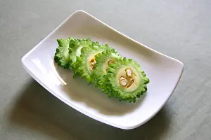 Flesh Prints: Green vegetable ; slices of karela bitter gourd momordica charantia in rectangle plate on grey background