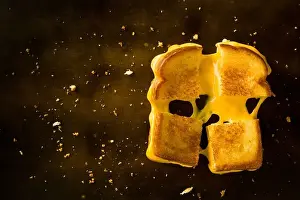Melted Prints: A Grilled Cheese Sandwich cut in four squares pulling the cheese on a wood table