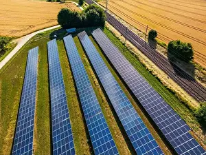 Solar Panels Prints: Ground-mounted system with solar cells and solar modules in the countryside next to a railroad line