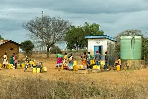 Fresh Water Prints: A group of African women and children queue to fill up water containers at a water kiosk in rural Kenya