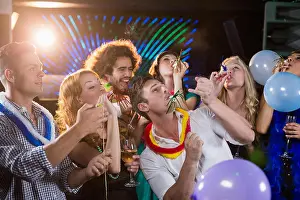 Amusing Prints: Group of friends blowing party horn in bar