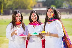 Indian People Prints: Group of happy young Indian woman friends wearing white kurta dress holding powder color plate celebrating holi