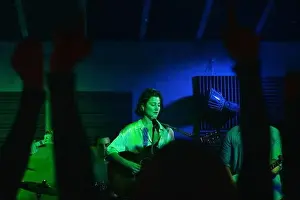 Illuminate Prints: Group of people in casual clothes playing guitars and drums while Woman singing