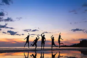 Teenagers Prints: group of people jumping on the beach at sunset, silhouette of friends having fun together